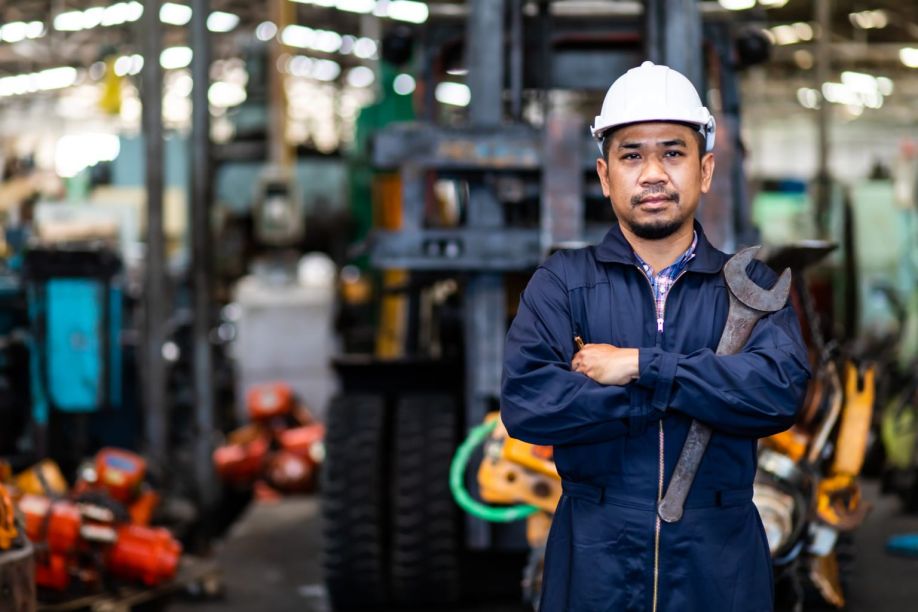 A machinist stands tall in his machine shop after a hard day of work.